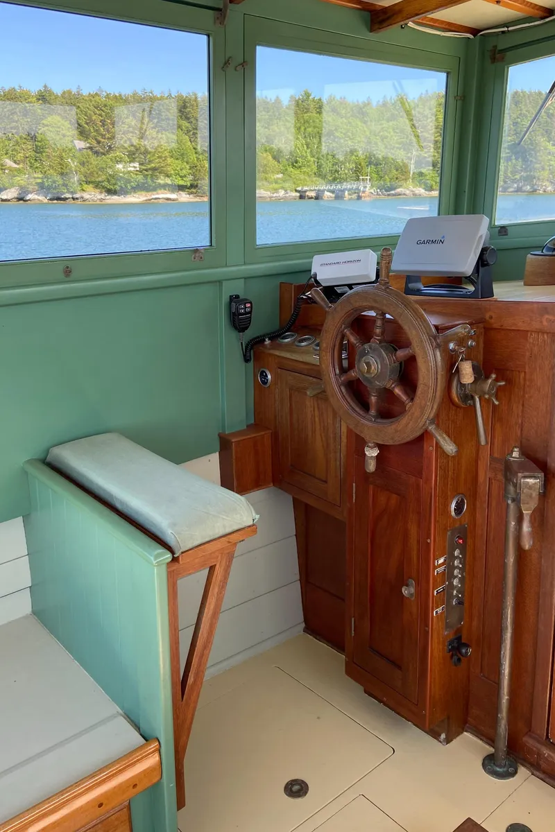 Slide: The Image of 1929 Classic Lobster Cruiser helm with wooden wheel and vintage controls, overlooking serene waters. - 9