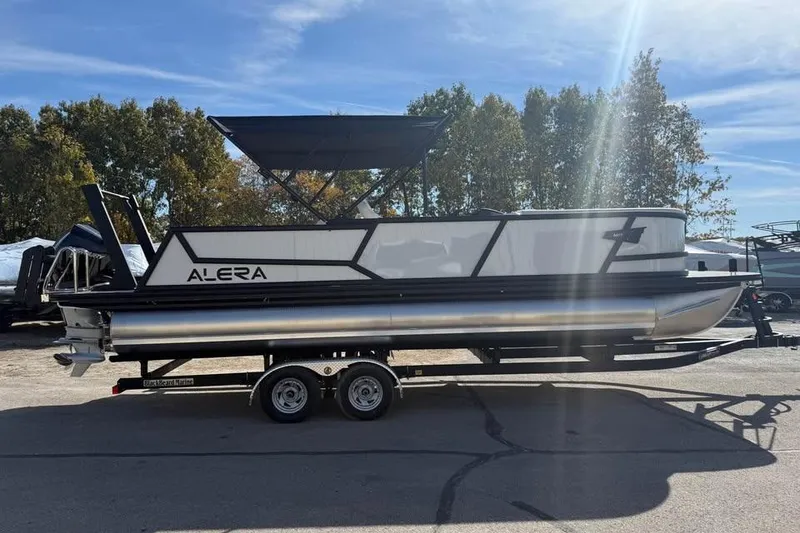 Slide: The Image of 2026 Alera M 25Q pontoon boat on trailer, parked outdoors under sunlight. - 4