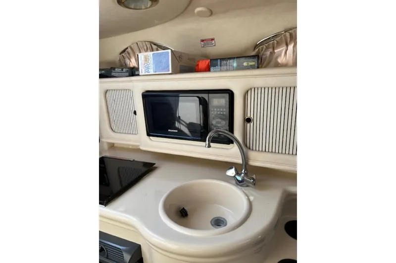 Slide: The Image of 2002 Sea Ray 260 Sundancer cabin kitchen with sink, microwave, and storage cabinets. - 17