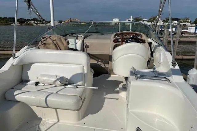 Slide: The Image of 2002 Sea Ray 260 Sundancer boat interior with seating and steering wheel, docked by the water. - 4
