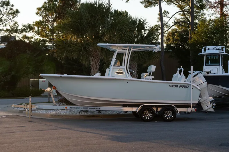 The Image of 2026 Sea Pro 225FLX Sandbar boat on trailer, parked outdoors near trees. - 1