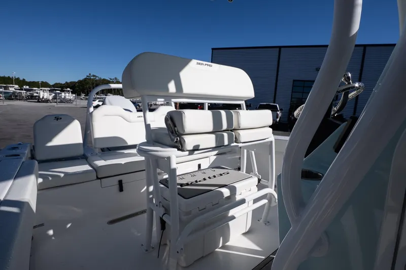 Slide: The Image of 2026 Sea Pro 225FLX Sandbar boat interior with seating and storage, in a marina setting. - 18
