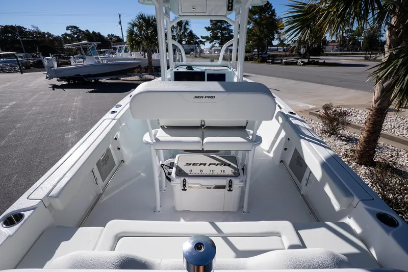 Slide: The Image of 2026 Sea Pro 225FLX Sandbar boat interior with seating and console, parked outdoors. - 8