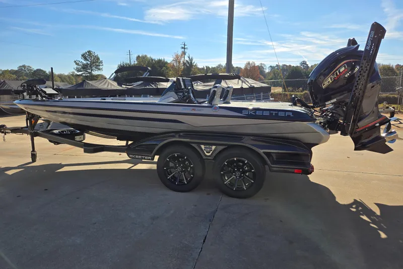 Slide: The Image of 2025 Skeeter FXR20 PRO boat on trailer, parked outdoors under clear sky. - 12