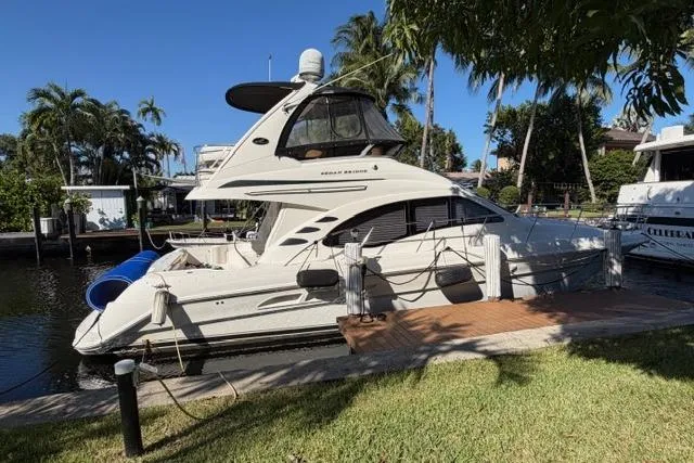 The Image of 2004 Sea Ray 420 Sedan Bridge yacht docked by lush greenery and palm trees. - 0