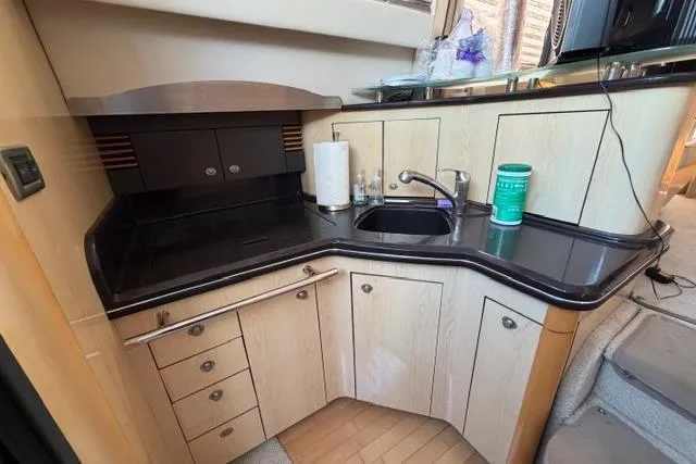 Slide: The Image of 2004 Sea Ray 420 Sedan Bridge kitchen with sleek black countertops and modern cabinetry. - 10