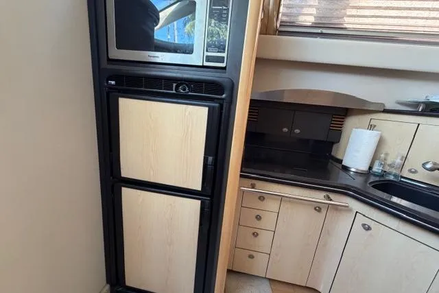 Slide: The Image of Kitchen area of 2004 Sea Ray 420 Sedan Bridge with microwave and cabinetry. - 11