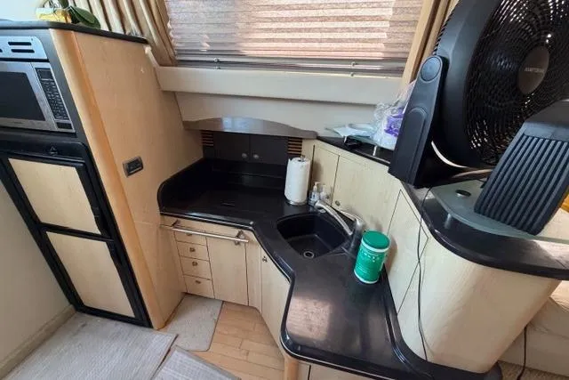 Slide: The Image of 2004 Sea Ray 420 Sedan Bridge kitchen with black countertops and modern appliances. - 12