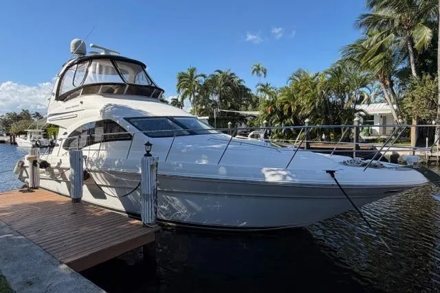 Slide: The Image of 2004 Sea Ray 420 Sedan Bridge yacht docked by palm trees under blue sky. - 2