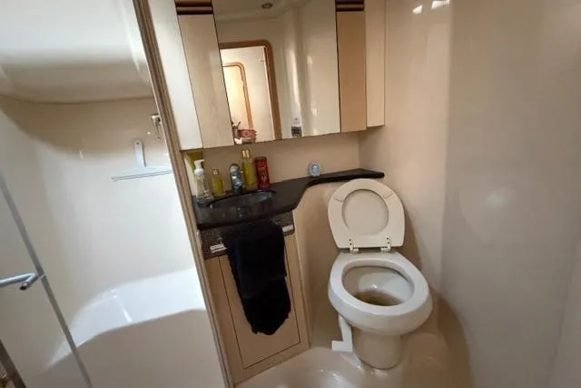 Slide: The Image of 2004 Sea Ray 420 Sedan Bridge bathroom with toilet, sink, and storage cabinets. - 21