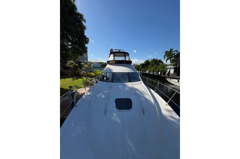 Slide: The Image of 2004 Sea Ray 420 Sedan Bridge yacht docked by a canal under clear blue sky. - 3