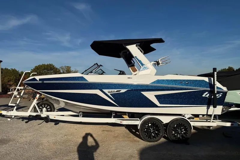 The Image of 2026 Tigé 22RZX boat on trailer, blue and white design, parked outdoors. - 0