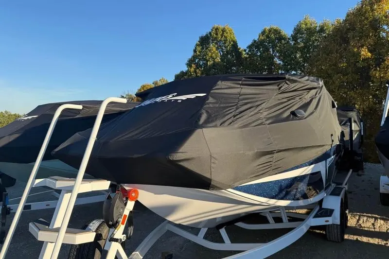 Slide: The Image of 2026 Tigé 22RZX boat covered, parked on trailer, surrounded by trees. - 17