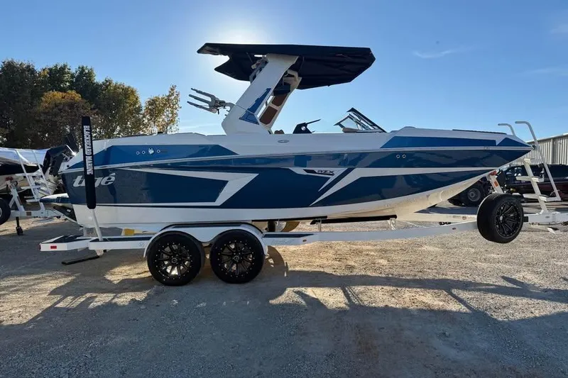 Slide: The Image of 2026 Tigé 22RZX boat on trailer, blue and white design, parked outdoors. - 4