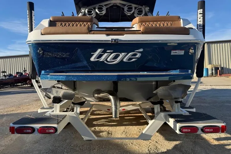 Slide: The Image of 2026 Tigé 22RZX boat rear view, blue hull, parked outdoors. - 7