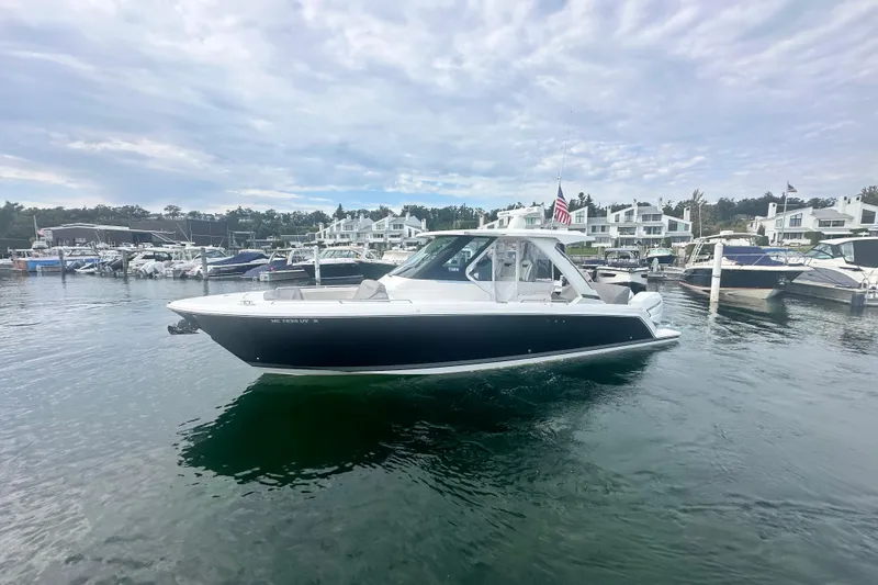 Slide: The Image of 2023 Tiara Yachts 34 LS in marina, surrounded by boats and waterfront homes. - 2