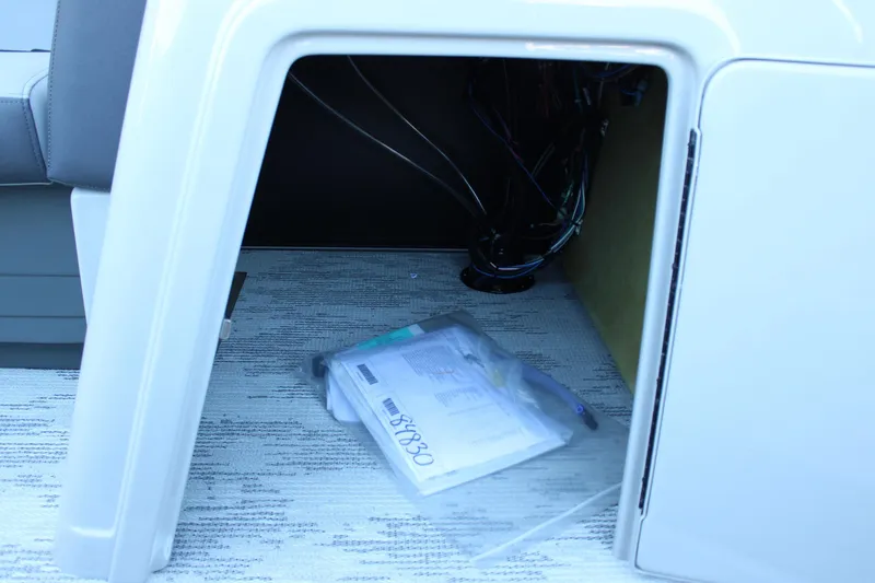 Slide: The Image of Interior storage compartment of 2026 Starcraft EXS 3 boat with visible wiring and documents. - 26