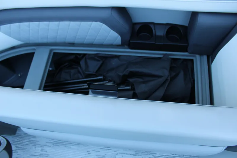 Slide: The Image of 2026 Starcraft EXS 3 boat storage compartment with black cover and cup holders. - 30