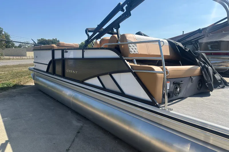 Slide: The Image of 2025 Crest Classic 240 pontoon boat with tan seating, docked outdoors. - 2