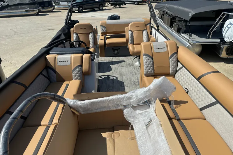 Slide: The Image of 2025 Crest Classic 240 pontoon boat interior with tan and gray seating, docked outdoors. - 3