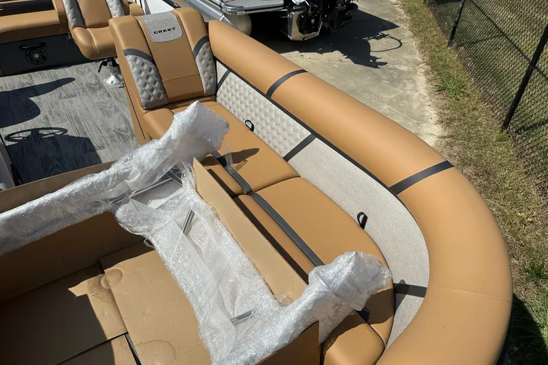 Slide: The Image of 2025 Crest Classic 240 boat interior with tan and gray seating, partially wrapped in plastic. - 4