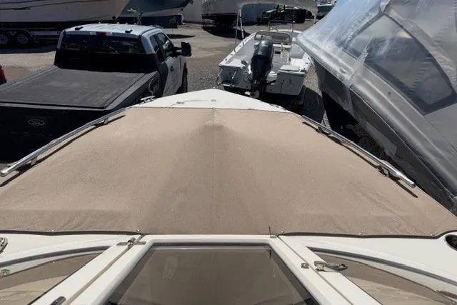 Slide: The Image of 2021 Scout 235 Dorado boat with beige cover, parked among other boats and vehicles. - 2