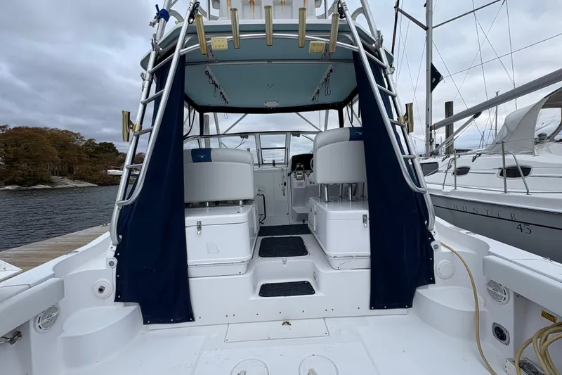 Slide: The Image of 2005 Pro-Line 33 Express boat interior with seating and fishing rod holders at a dock. - 10