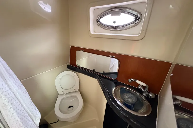 Slide: The Image of 2005 Pro-Line 33 Express boat bathroom with toilet, sink, and porthole window. - 23