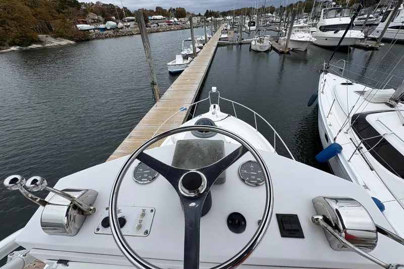 Slide: The Image of 2005 Pro-Line 33 Express boat helm at marina, surrounded by docked sailboats. - 32