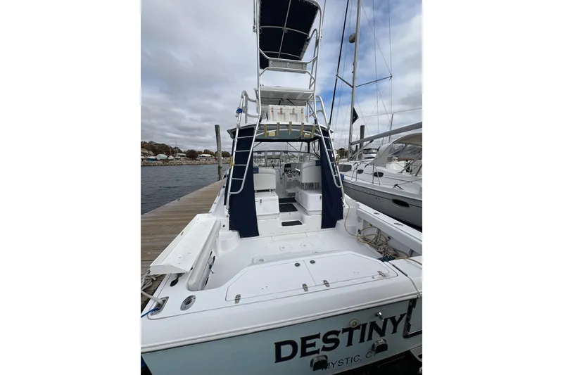 Slide: The Image of 2005 Pro-Line 33 Express boat docked, featuring spacious deck and tower under cloudy skies. - 8