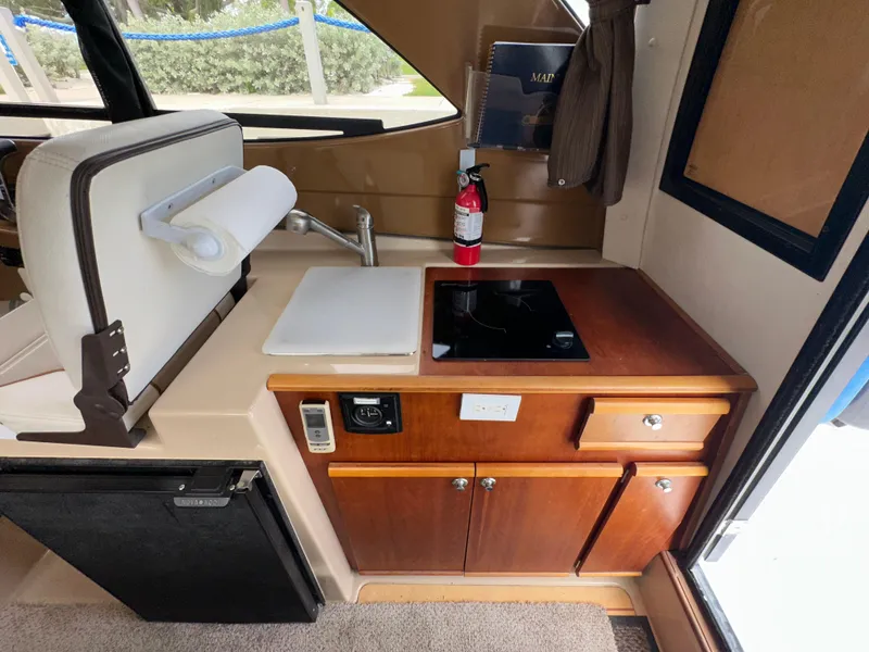 Slide: The Image of 2016 Cutwater C 24 Coupe interior kitchen with stove, sink, and storage cabinets. - 10