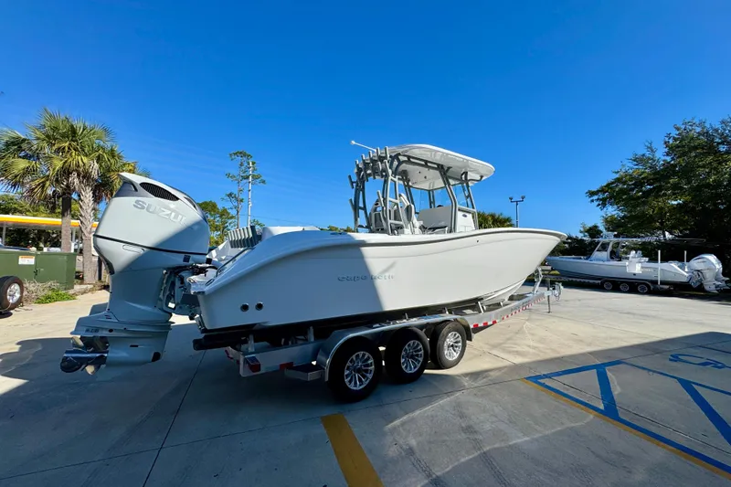 Slide: The Image of 2026 Cape Horn 32 XS boat on trailer with Suzuki outboard motor, parked outdoors. - 12