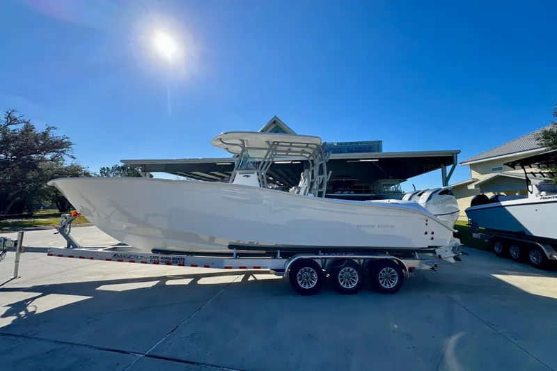 The Image of 2026 Cape Horn 32 XS boat on trailer under bright sun, parked near a building. - 1