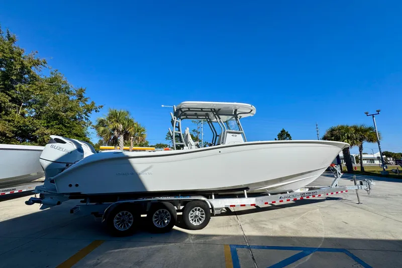 Slide: The Image of 2026 Cape Horn 32 XS boat on trailer, parked outdoors under clear blue sky. - 11