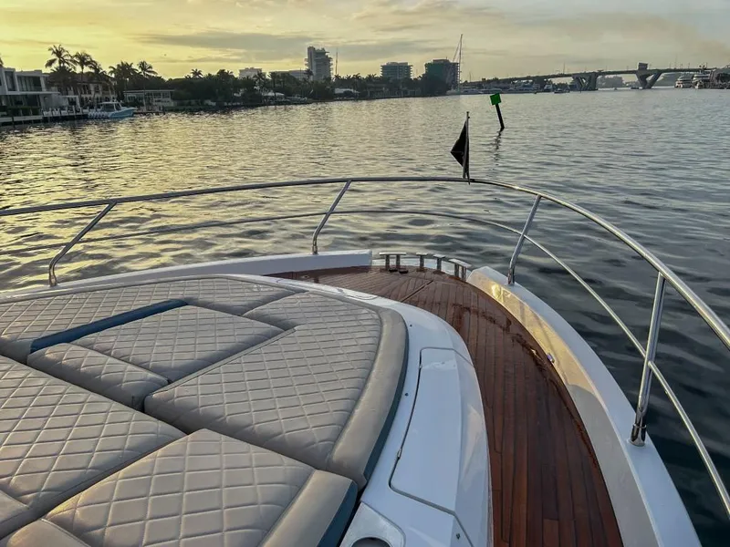 Slide: The Image of 2024 Fairline Squadron 68 yacht bow with sunpad, cruising on calm waters at sunset. - 6