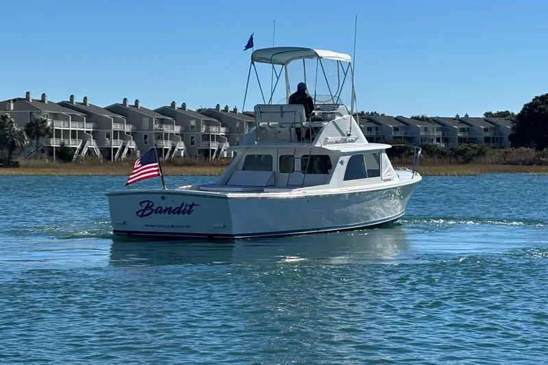 Slide: The Image of 1970 Bertram 31 Flybridge Cruiser "Bandit" on water near coastal homes. - 11