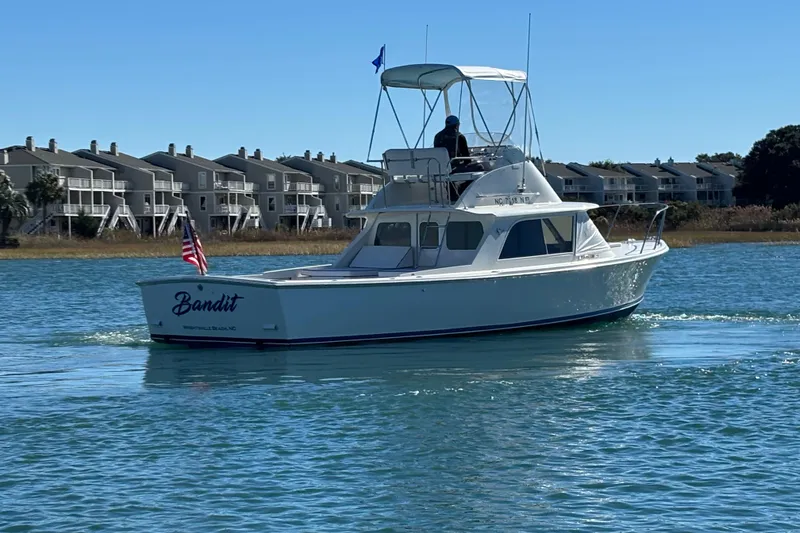 Slide: The Image of 1970 Bertram 31 Flybridge Cruiser "Bandit" on water near residential area. - 12