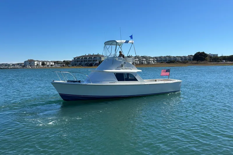 Slide: The Image of 1970 Bertram 31 Flybridge Cruiser on calm water, clear sky, American flag displayed. - 18