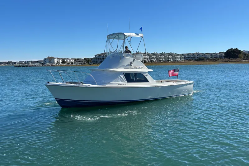Slide: The Image of 1970 Bertram 31 Flybridge Cruiser on calm water, American flag, clear sky. - 19