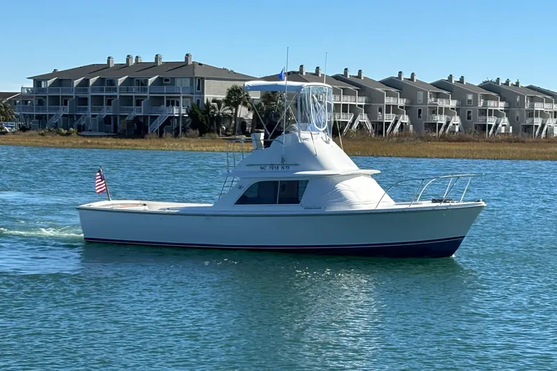 Slide: The Image of 1970 Bertram 31 Flybridge Cruiser on calm water, American flag displayed. - 2