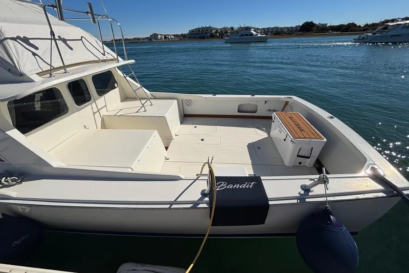 Slide: The Image of 1970 Bertram 31 Flybridge Cruiser docked, featuring spacious deck and scenic waterfront view. - 20