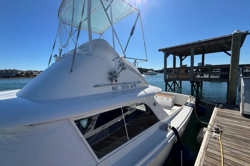 Slide: The Image of 1970 Bertram 31 Flybridge Cruiser docked at marina under clear blue sky. - 24