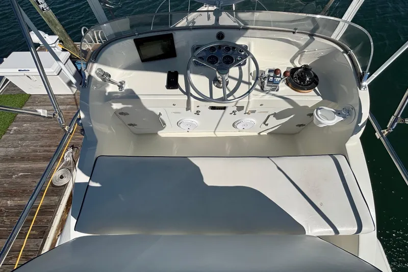 Slide: The Image of 1970 Bertram 31 Flybridge Cruiser helm with steering wheel and controls, docked by the water. - 32