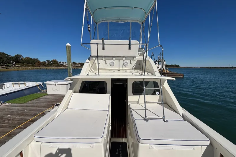 Slide: The Image of 1970 Bertram 31 Flybridge Cruiser docked, showcasing spacious deck and flybridge under clear blue sky. - 33