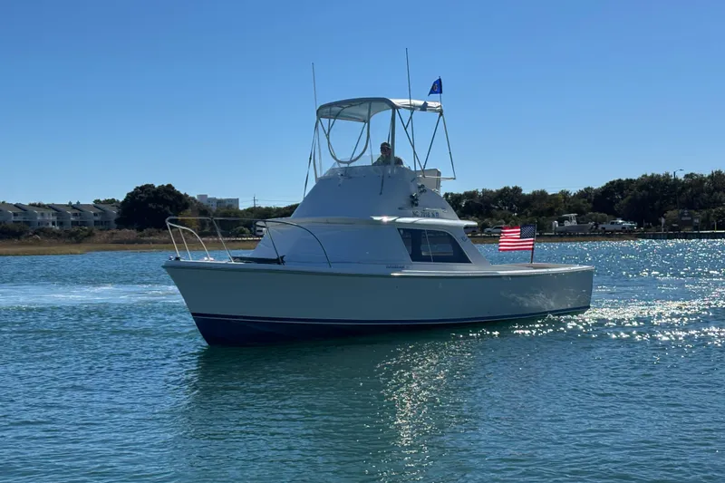 Slide: The Image of 1970 Bertram 31 Flybridge Cruiser on water near waterfront homes. - 6