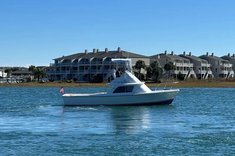 Slide: The Image of 1970 Bertram 31 Flybridge Cruiser on water, with residential buildings in background. - 8
