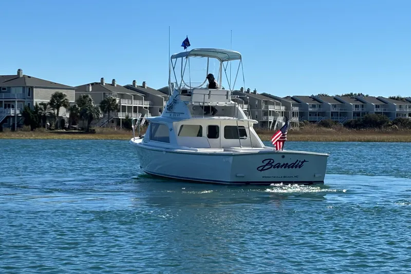 Slide: The Image of 1970 Bertram 31 Flybridge Cruiser on water near coastal homes. - 9