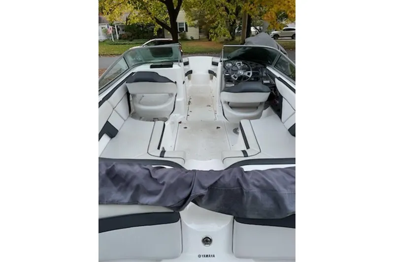 Slide: The Image of 2015 Yamaha Boats SX210 interior with seating and steering wheel, parked outdoors. - 6