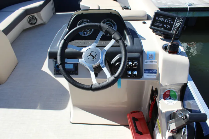Slide: The Image of 2025 Harris Cruiser 230 boat dashboard with steering wheel and navigation controls. - 17