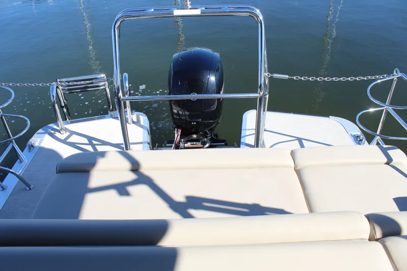 Slide: The Image of 2025 Harris Cruiser 230 boat with outboard motor, beige seating, and stainless steel railings on water. - 21